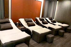 A room with multiple massage beds arranged in a row, each with a pillow and a footrest. - Nvshu Hotel (Jiangyong)