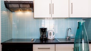 A kitchen with white cabinets, a black stove, a coffee maker, and a sink. - 2007 Garden Chic, Heated Pool (San Eugenio Alto)