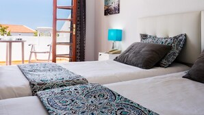 A hotel room with two beds, a balcony with a table and chairs, a nightstand with a lamp, and a wall with a framed picture. - 2007 Garden Chic, Heated Pool (San Eugenio Alto)