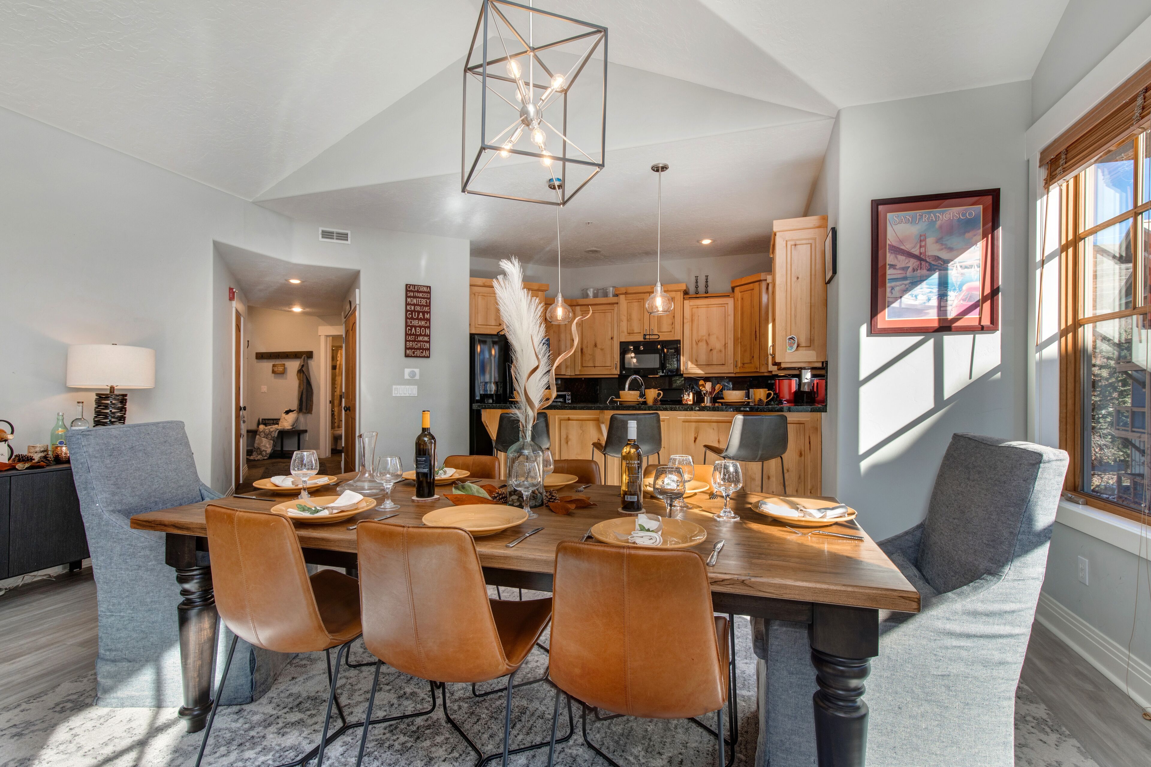 A dining area with a wooden table, leather chairs, and pendant lighting.