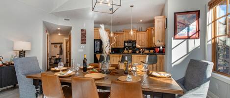 A dining area with a wooden table, leather chairs, and pendant lighting.