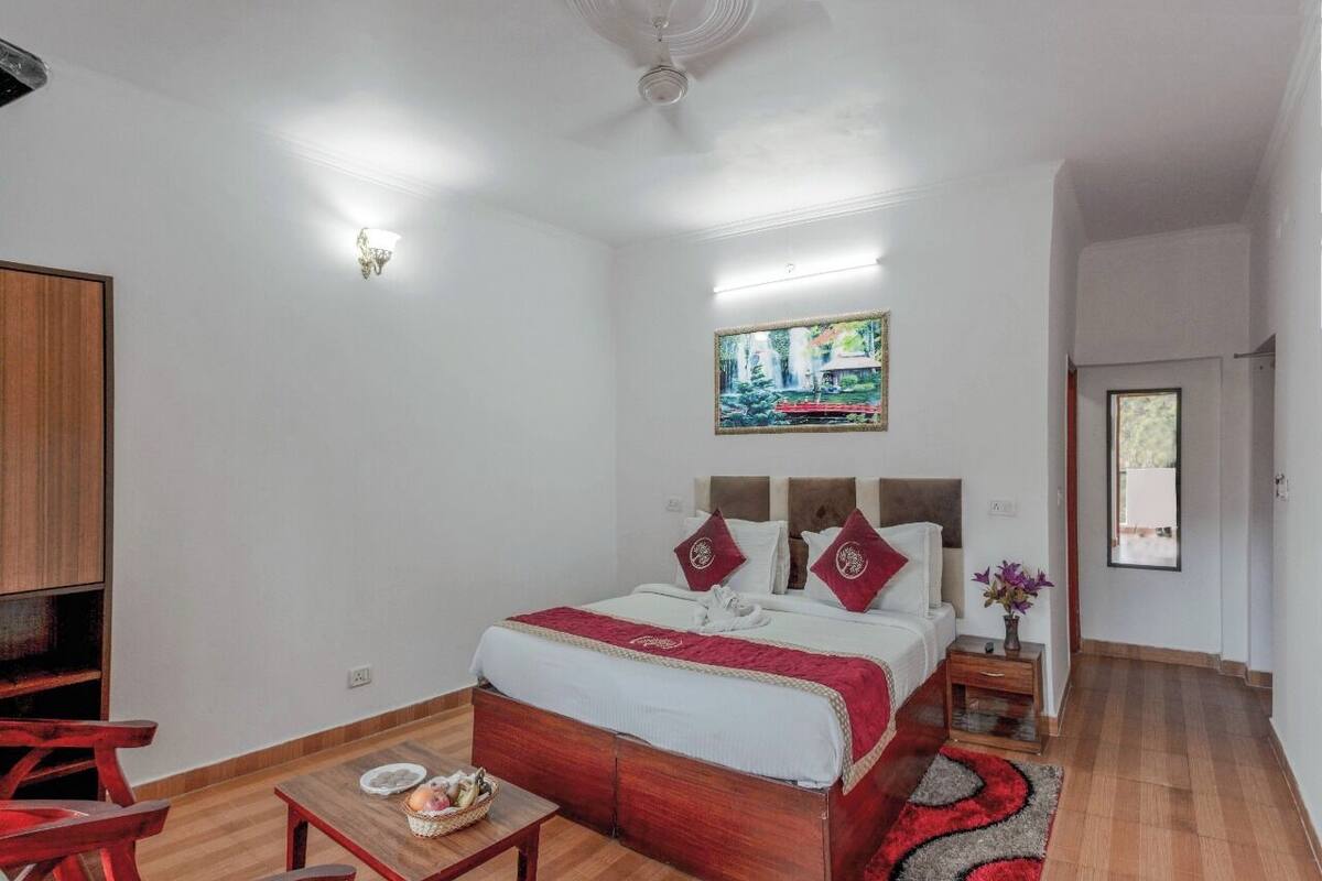 Een hotelkamer met een houten bed, een tafeltje met een mand, een schilderij aan de muur en een raam.