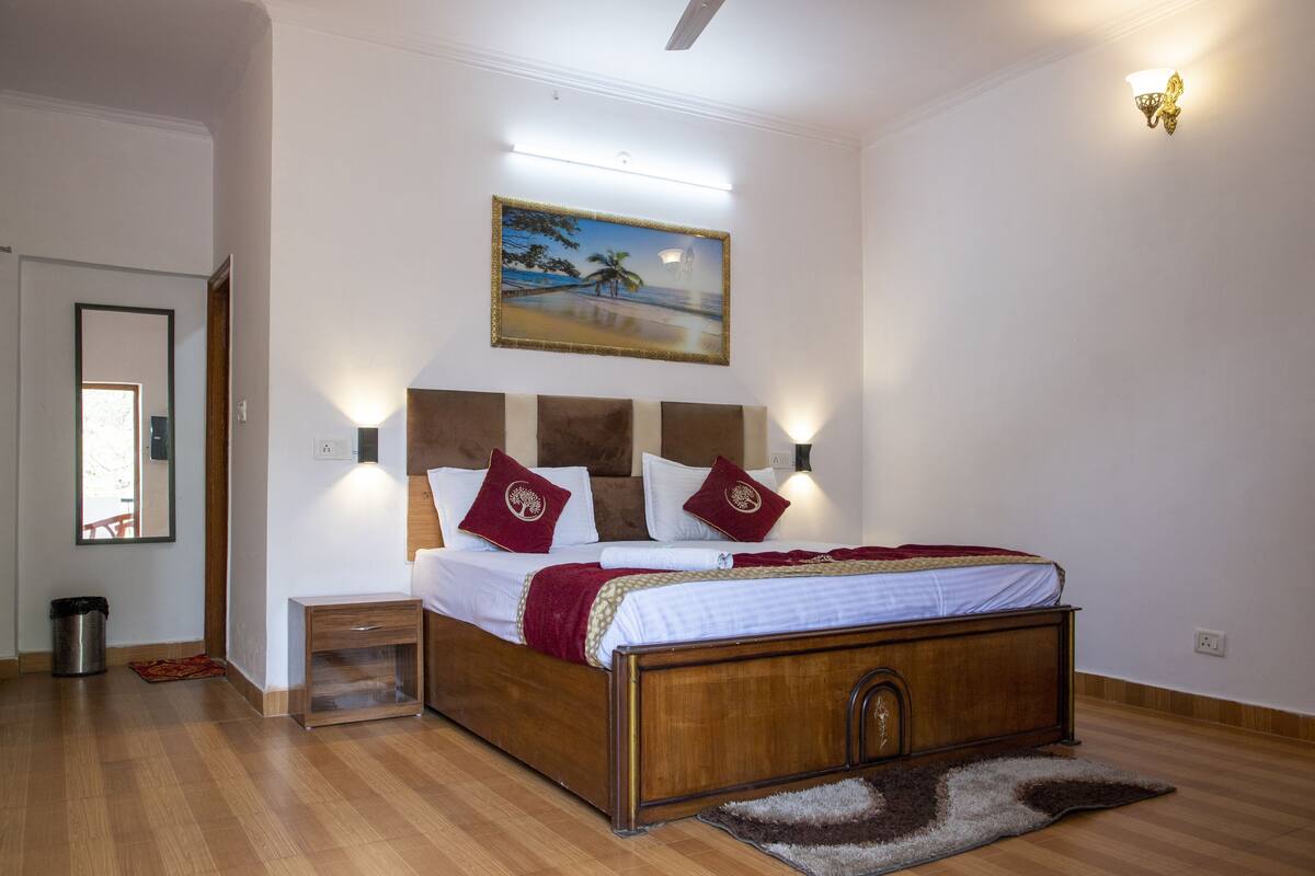 Een slaapkamer met een houten bed, witte wanden en een schilderij van een strandgezicht.