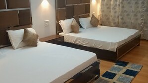 Une chambre d’hôtel avec deux lits, un plancher en bois et un rideau à motifs.