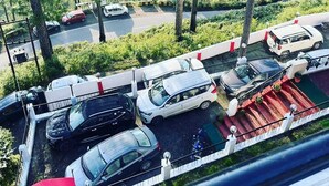 Un espace de stationnement avec plusieurs voitures et une passerelle piétonne rouge.