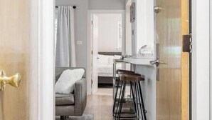 A modern kitchen with bar stools, a dining table, and a view into the living area. - Inviting Stylish Home with Covered Patio (Chicago)