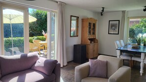 A living room with a sofa, armchair, dining table, and a cabinet. - Very spacious and cosy holiday home (Venlo)