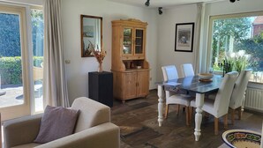 A dining area with a table, chairs, a cabinet, and a sofa. - Very spacious and cosy holiday home (Venlo)