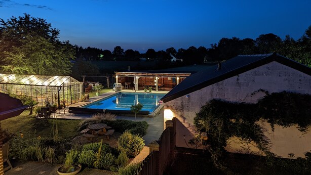 A backyard with a swimming pool, a greenhouse, and a wooden deck. - Very spacious and cosy holiday home (Venlo)