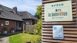 A house with a sign reading 'welkom la bienvenue eten & slapen' and a license plate 'IV LICENCE LOI DU 24 SEPTEMBRE 1941'. - Very spacious and cosy holiday home (Venlo)