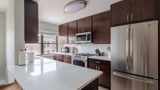 A modern kitchen with dark wood cabinets, stainless steel appliances, and a large island.