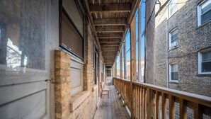A corridor with wooden flooring, a wooden railing, and brick walls. - Beautiful and Comfy 1BR in Lincoln Square (Chicago)