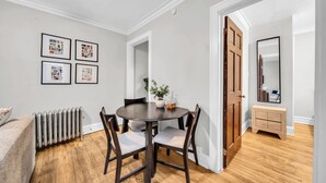 A dining area with a round table, chairs, a potted plant, and framed pictures on the wall. - Beautiful and Comfy 1BR in Lincoln Square (Chicago)