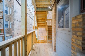 Staircase leads to an upper floor with a balcony offering a view of the street below.