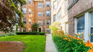 A courtyard with a well-maintained lawn, a pathway, and a row of orange flowers. - Stylish and Comfy Retreat 10 Minutes from Wrigley (Chicago)