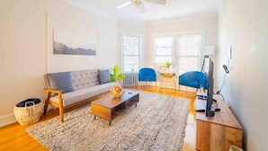 A living room with a sofa, coffee table, and TV stand. - Stylish and Comfy Retreat 10 Minutes from Wrigley (Chicago)