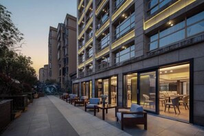 A hotel with outdoor seating, large windows, and a modern design. - Hengchu Sunshine Hotel (Ningxiang)