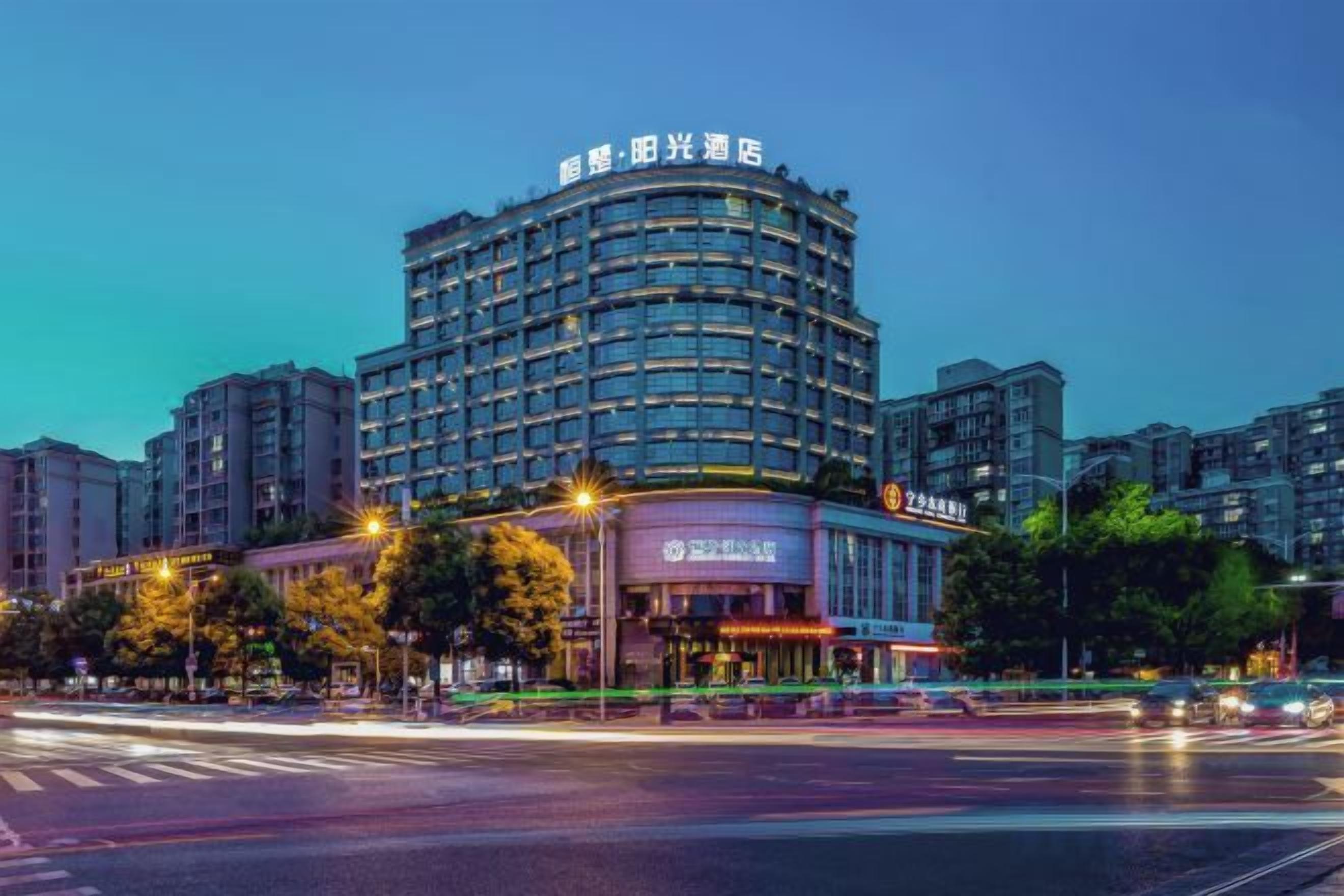 Un hotel de varios pisos con fachada curva, señalización iluminada y una entrada visible.