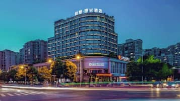 A multi-story hotel with a curved facade, illuminated signage, and a visible entrance.
