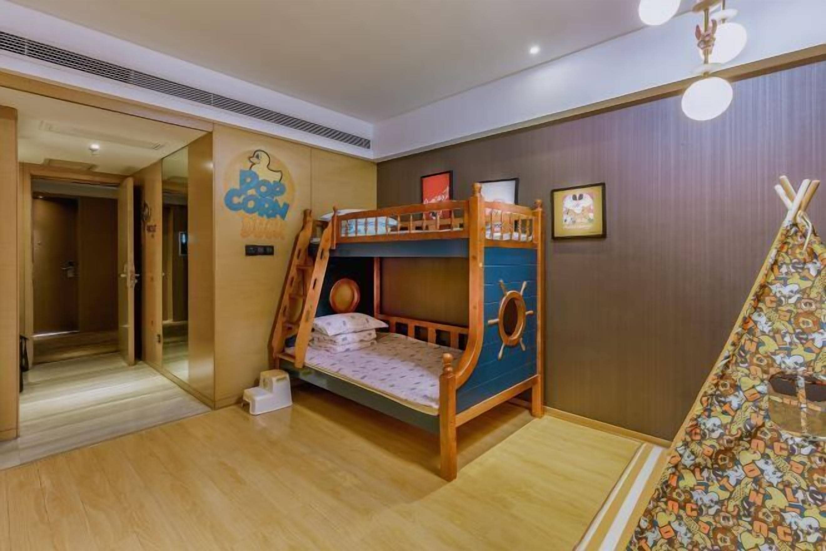 A bunk bed room with a wooden ladder, a small table, and a tent-like decoration.
