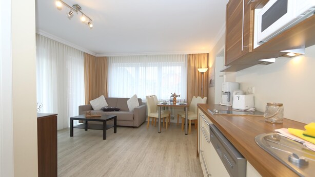 A modern kitchen with a dining area, wooden cabinets, and a built-in microwave. - House Sarah 05, Germany (Sylt)