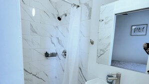 A bathroom with a shower, a sink, and a mirror.