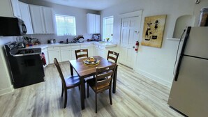A compact kitchen with white cabinets, a black stove, and a dining table with chairs.