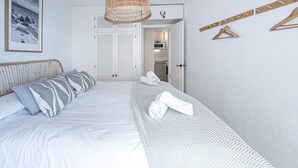 A bedroom with a bed, a hanging wicker light fixture, a wardrobe, and a towel rack. - Acapulco Playa 302 by Casasol (Nerja)