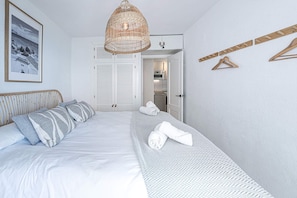 Ein Schlafzimmer mit einem Bett, einer hängenden Korbschrankleuchte, einem Kleiderschrank und einem Handtuchhalter.