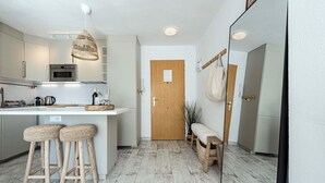A modern kitchen with a central island, bar stools, a wooden bench, and a hanging plant. - Acapulco Playa 302 by Casasol (Nerja)