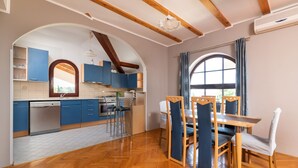 Uma cozinha moderna com armários azuis, uma mesa de jantar de madeira e uma janela grande com cortinas.