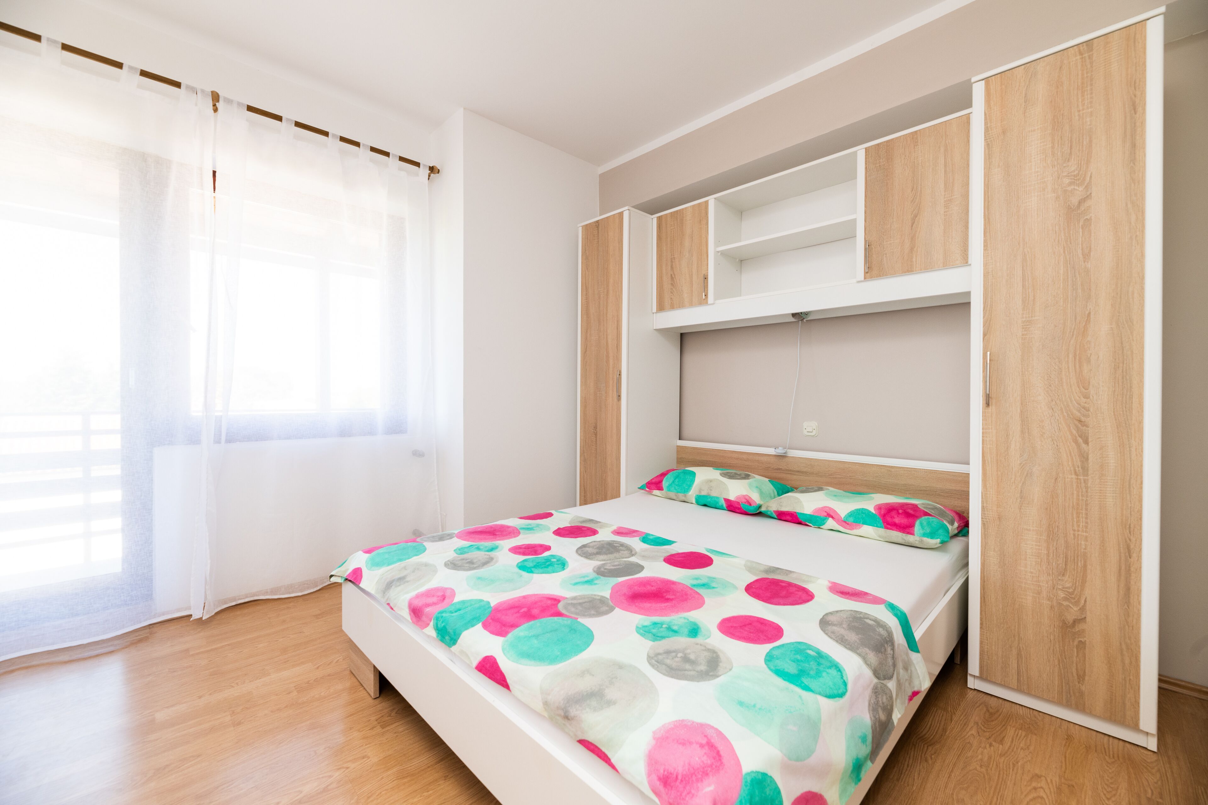 Une chambre à coucher avec un lit, une armoire et une fenêtre avec des rideaux.