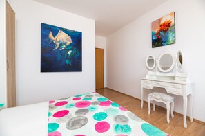 Ein Schlafzimmer mit einem Bett, einer Kommode mit Spiegel und zwei Bildern an der Wand.
