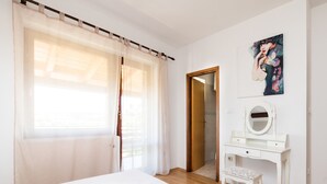 Quarto com cama, penteadeira com espelho e um quadro na parede.