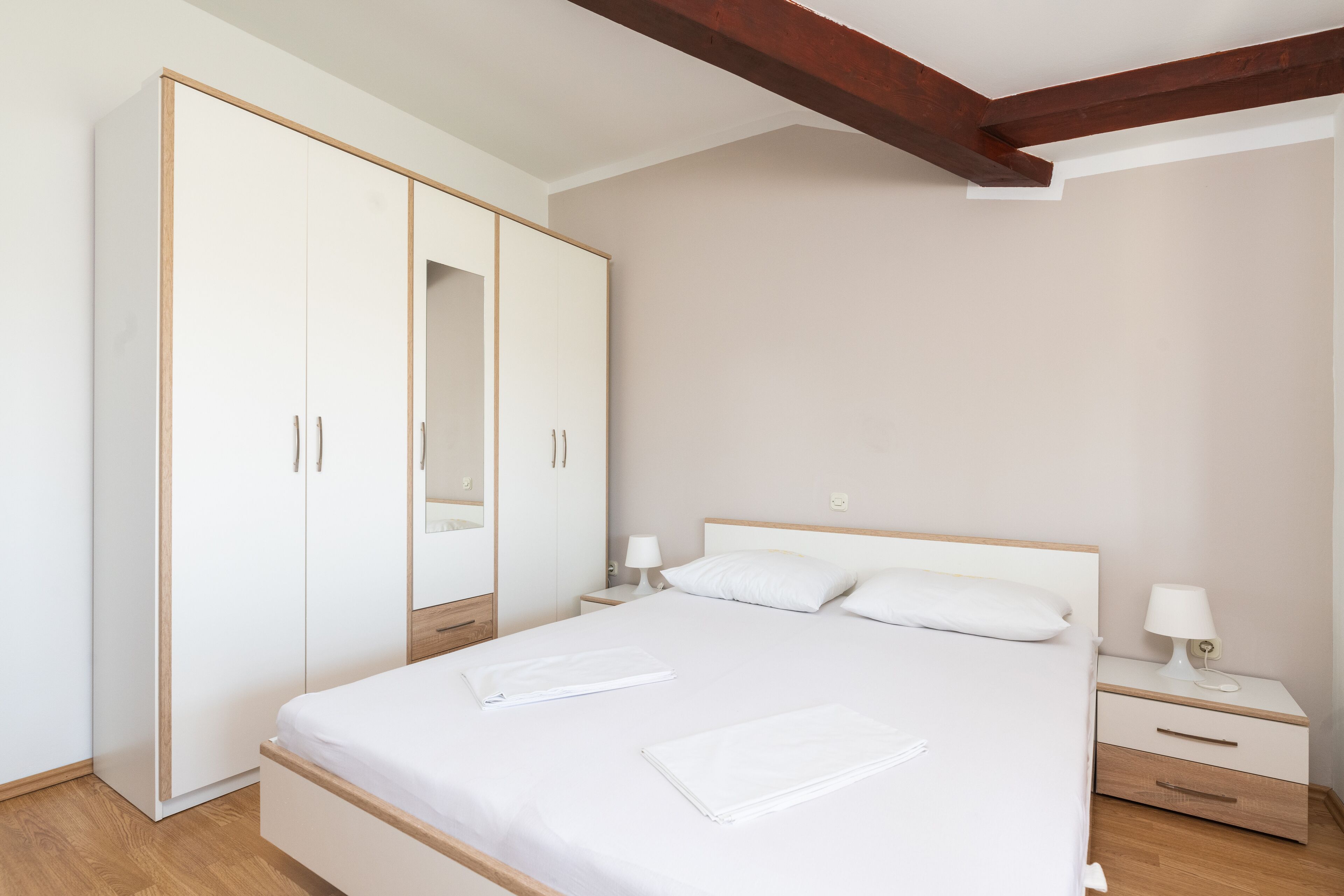 A bedroom with a bed, nightstands, a wardrobe, and a mirror.