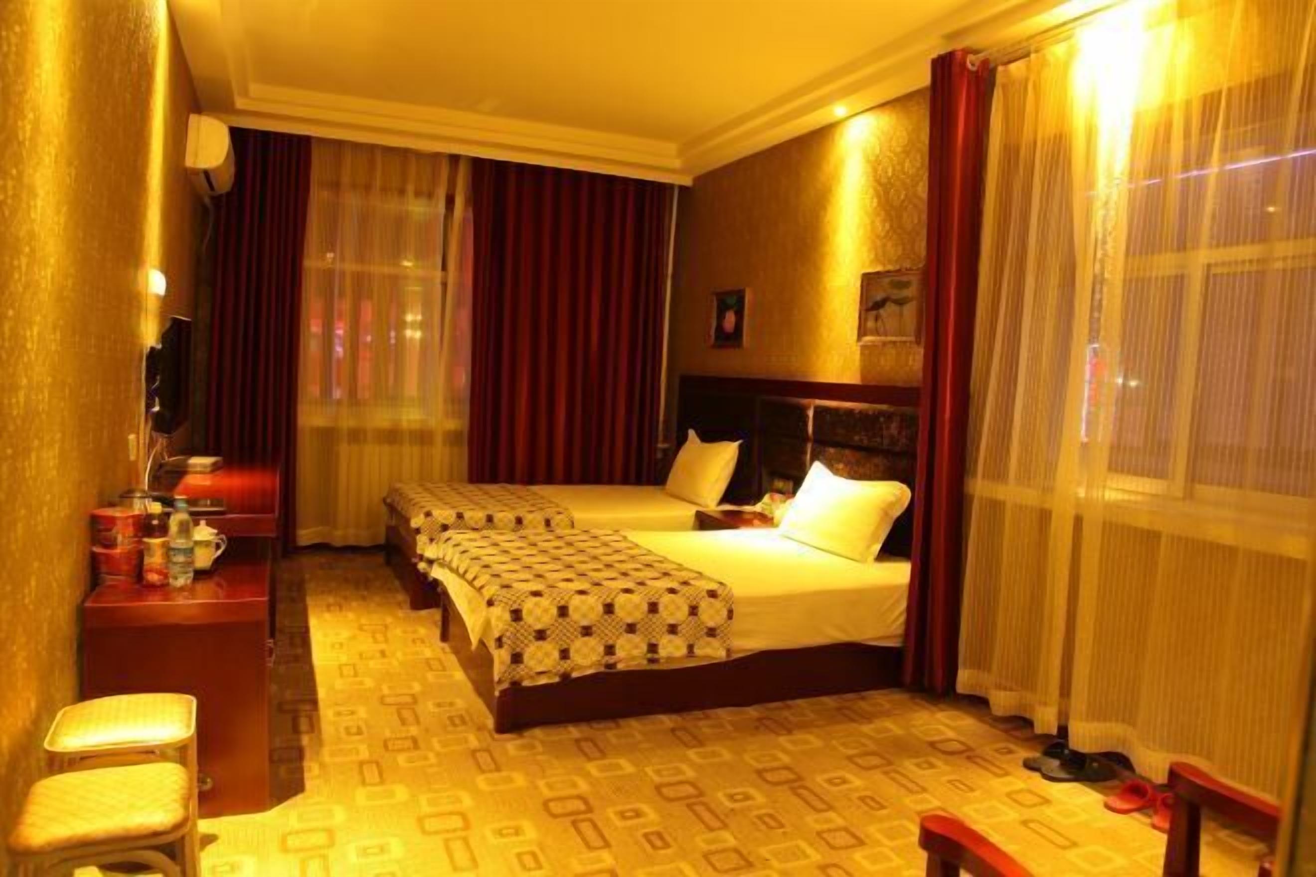 A hotel room with two beds, a desk, a chair, and a television.