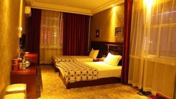 A hotel room with two beds, a desk, a chair, and a television.
