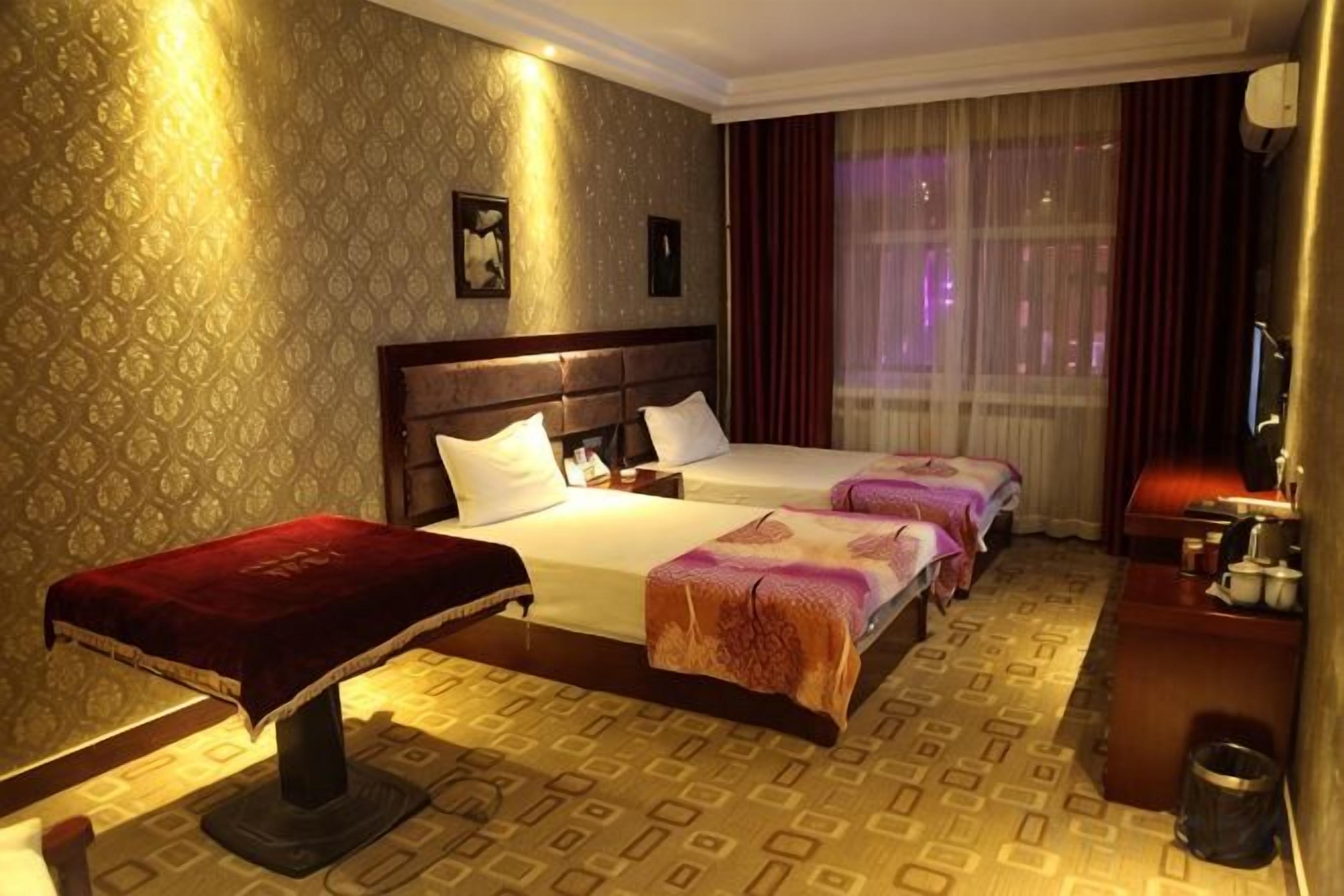 Une chambre d’hôtel avec un grand lit, deux petits lits, un bureau et une chaise.