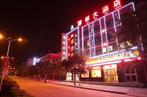 Un hotel con señalización iluminada, una estructura de varios pisos y una entrada bien iluminada.