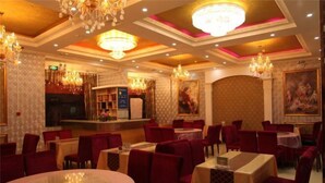 A restaurant with round tables, red upholstered chairs, and chandeliers. - Yongchang Lidu Hotel (Yongchang)