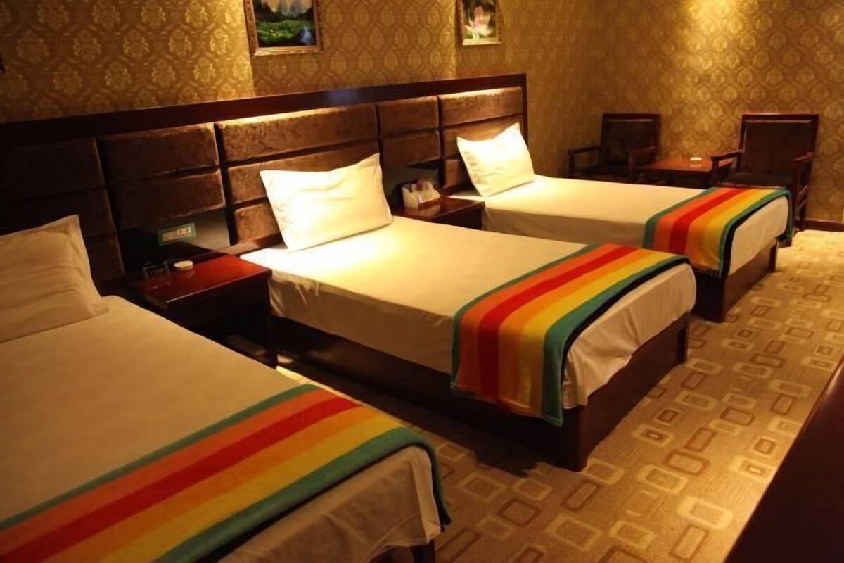 Ein Hotelzimmer mit zwei Betten, einem Kopfteil, Nachttischen und einem gemusterten Teppich.
