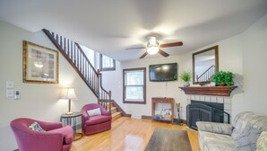 Ein Wohnzimmer mit Treppe, Kamin und Fernseher.