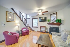 Ein Wohnzimmer mit Treppe, Kamin und Fernseher.