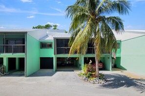 A two-story building with a green exterior and a central courtyard. - Mariners House @ Landings of Largo (Key Largo)