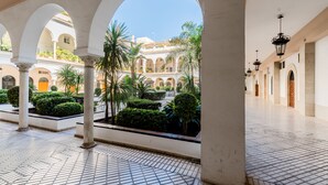 An open courtyard with tiled flooring, white columns, and arches. - Ponce Léon. 1-bedroom, private terrace. (Sevilla)