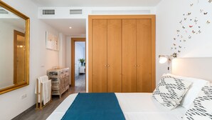 A bedroom with a large bed, a wooden wardrobe, a mirror, and a wall with butterfly decals. - Ponce Léon. 1-bedroom, private terrace. (Sevilla)