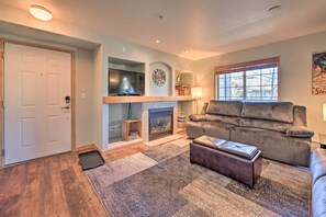 A living room with a fireplace, a sofa, and a television. - Steamboat Home w/ Garage, 1 Mi to Ski Resort (Steamboat Springs)