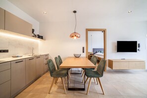 A modern kitchen with a dining table, chairs, and a TV mounted on the wall.