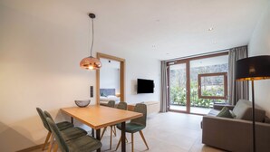 Ein modernes Wohnzimmer mit Essbereich, einer Couch, einem Fernseher und einem großen Fenster mit Blick.