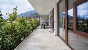 Ein modernes Gebäude mit überdachter Außenbereich, Tisch und Stühlen und Blick auf Berge.